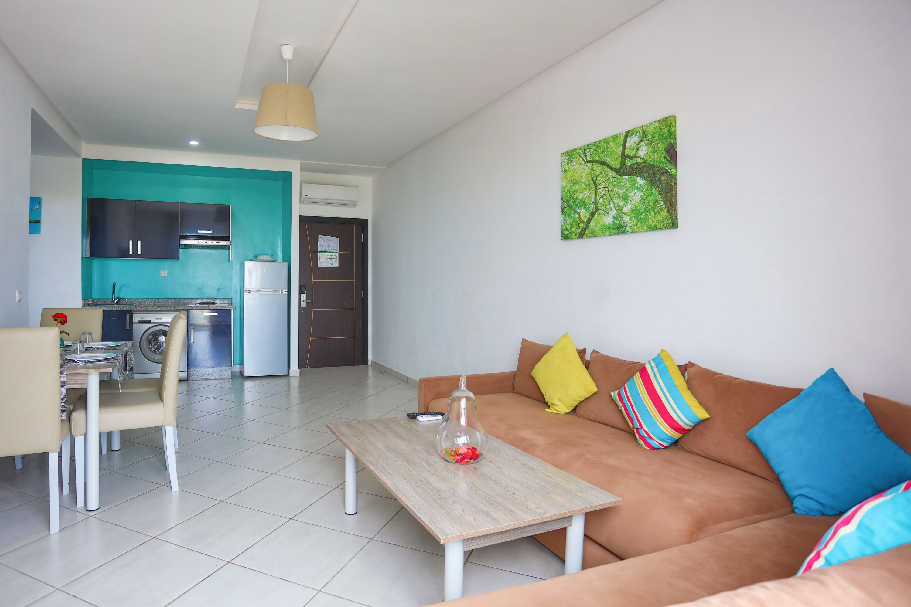 A modern living room with a sofa, a coffee table, and a dining area with chairs and a table.
