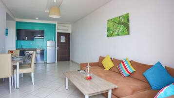 A modern living room with a sofa, a coffee table, and a dining area with chairs and a table.
