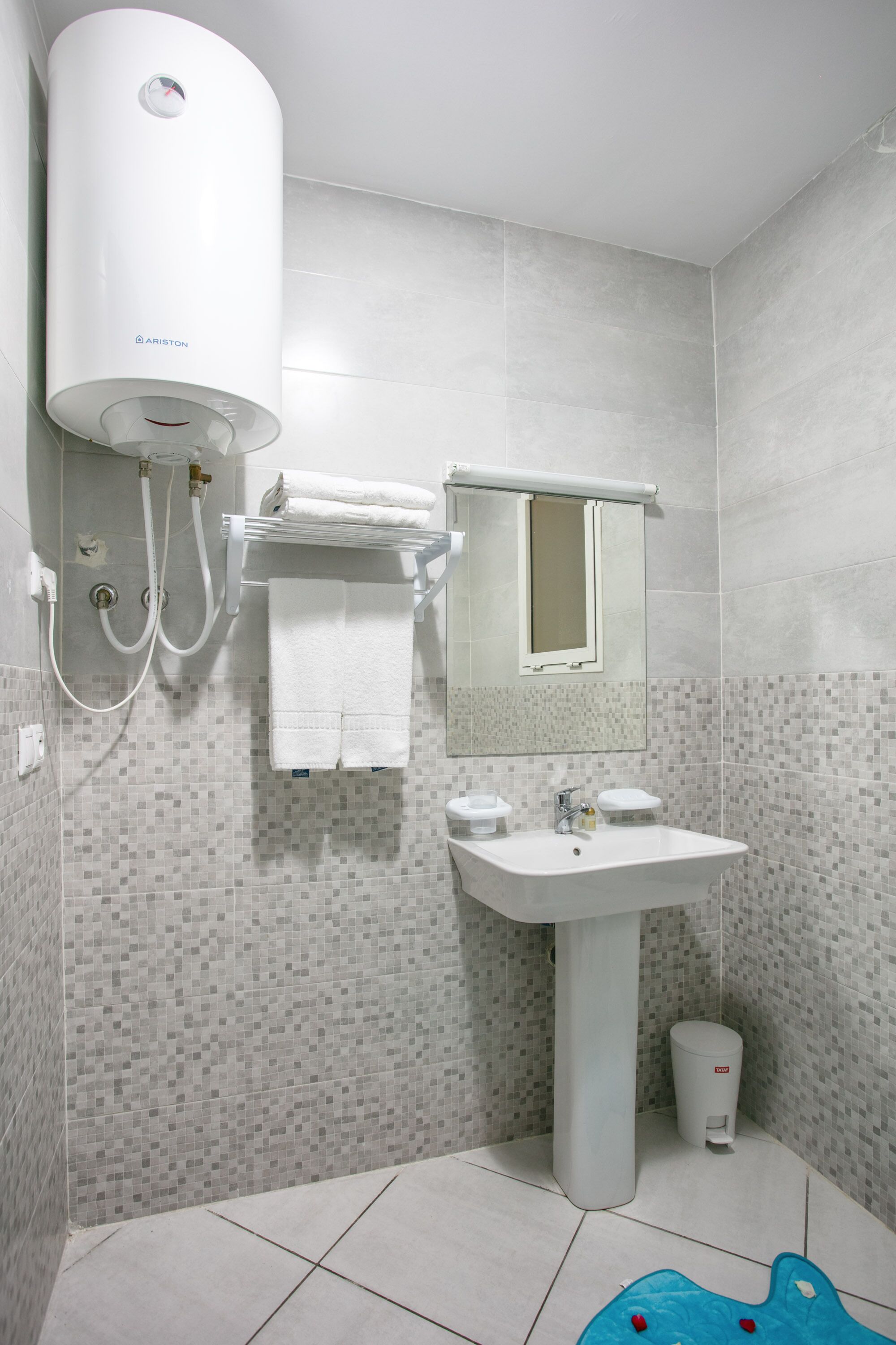 A bathroom with a white toilet, a sink, a mirror, and a shower unit.