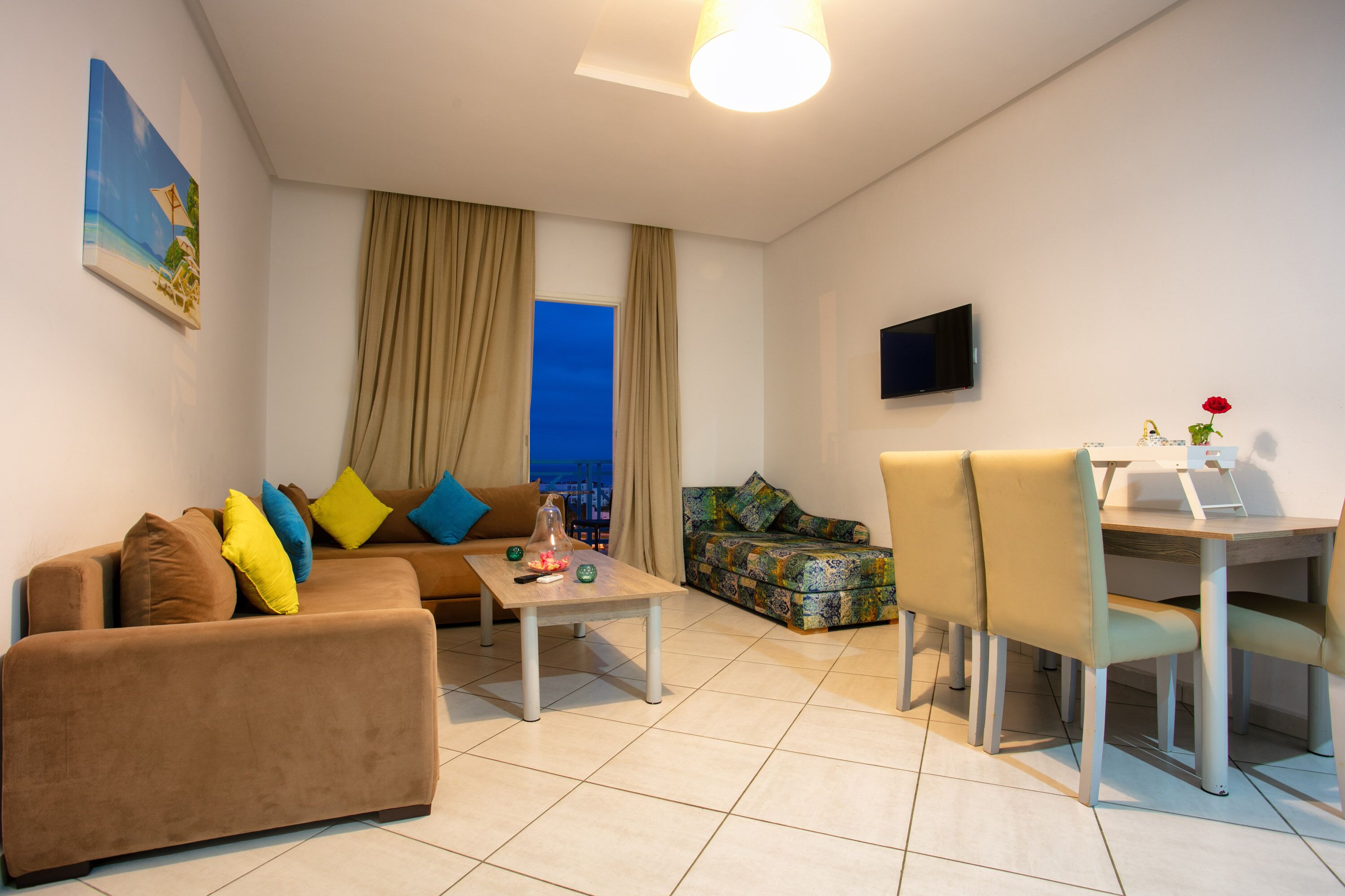 A modern living room with a sofa, a coffee table, a patterned sofa, and a dining area with chairs.