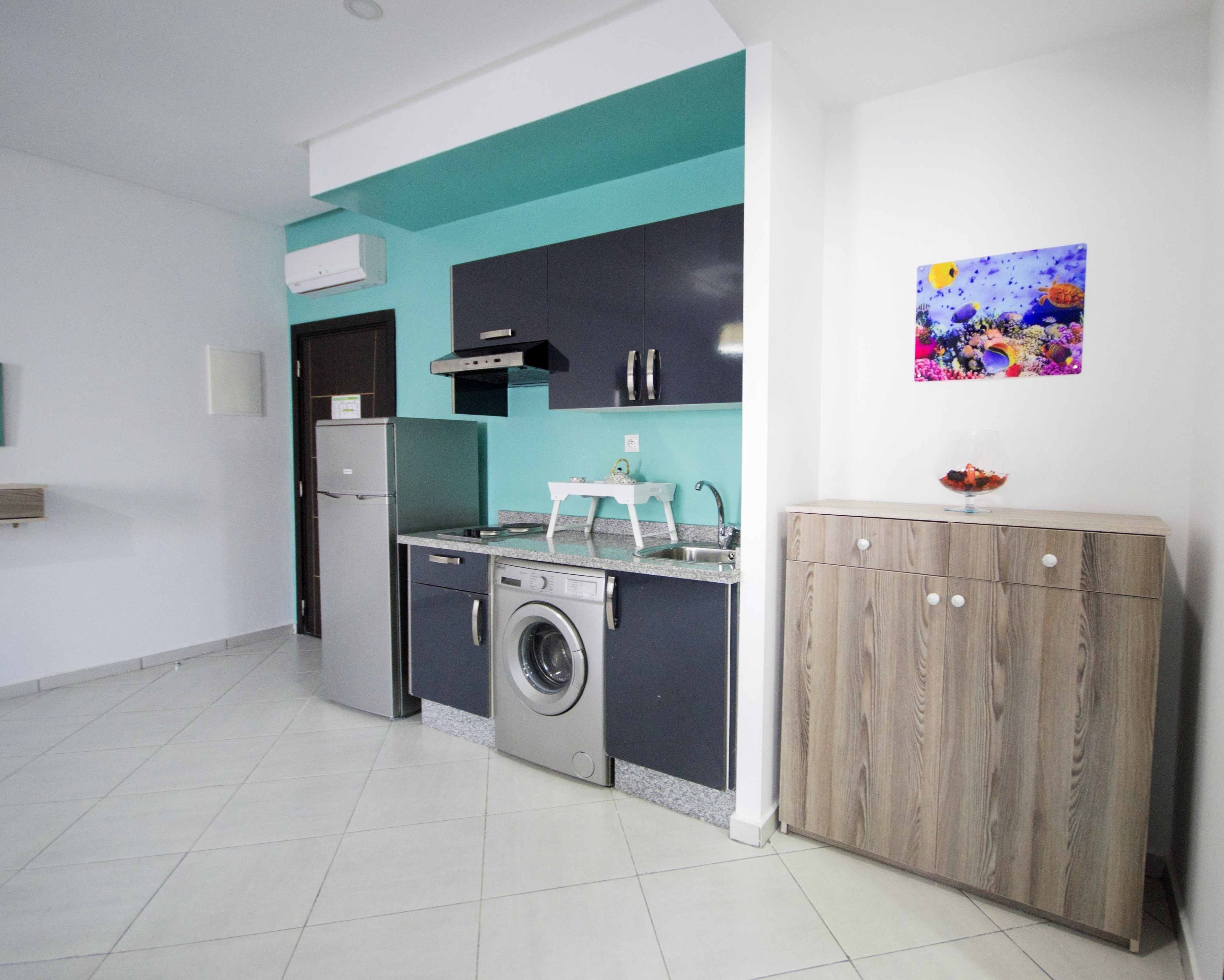 Een moderne keuken met een wasmachine, een spoelbak en een houten kast.