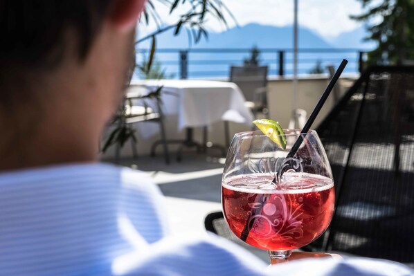 A glass of red drink with a straw and a lime slice on a table outdoors.