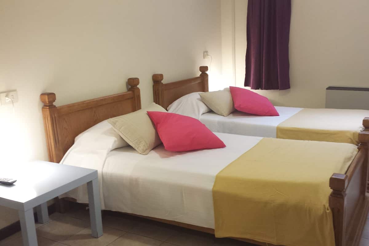 Two single beds with wooden headboards, a bedside table, and a radiator.