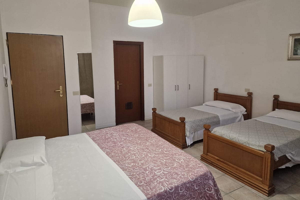 A room with two wooden beds, a wardrobe, a door, and a hanging light fixture.