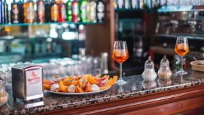 A bar counter with a plate of fruit, two glasses of a red beverage, and a salt and pepper shaker.