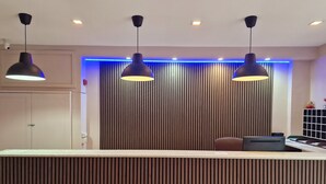 A reception area with a wooden slat wall, three pendant lights, and a reception desk.