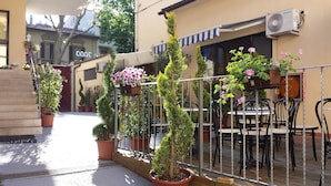 A courtyard with potted plants, outdoor seating, and a clock on the wall.