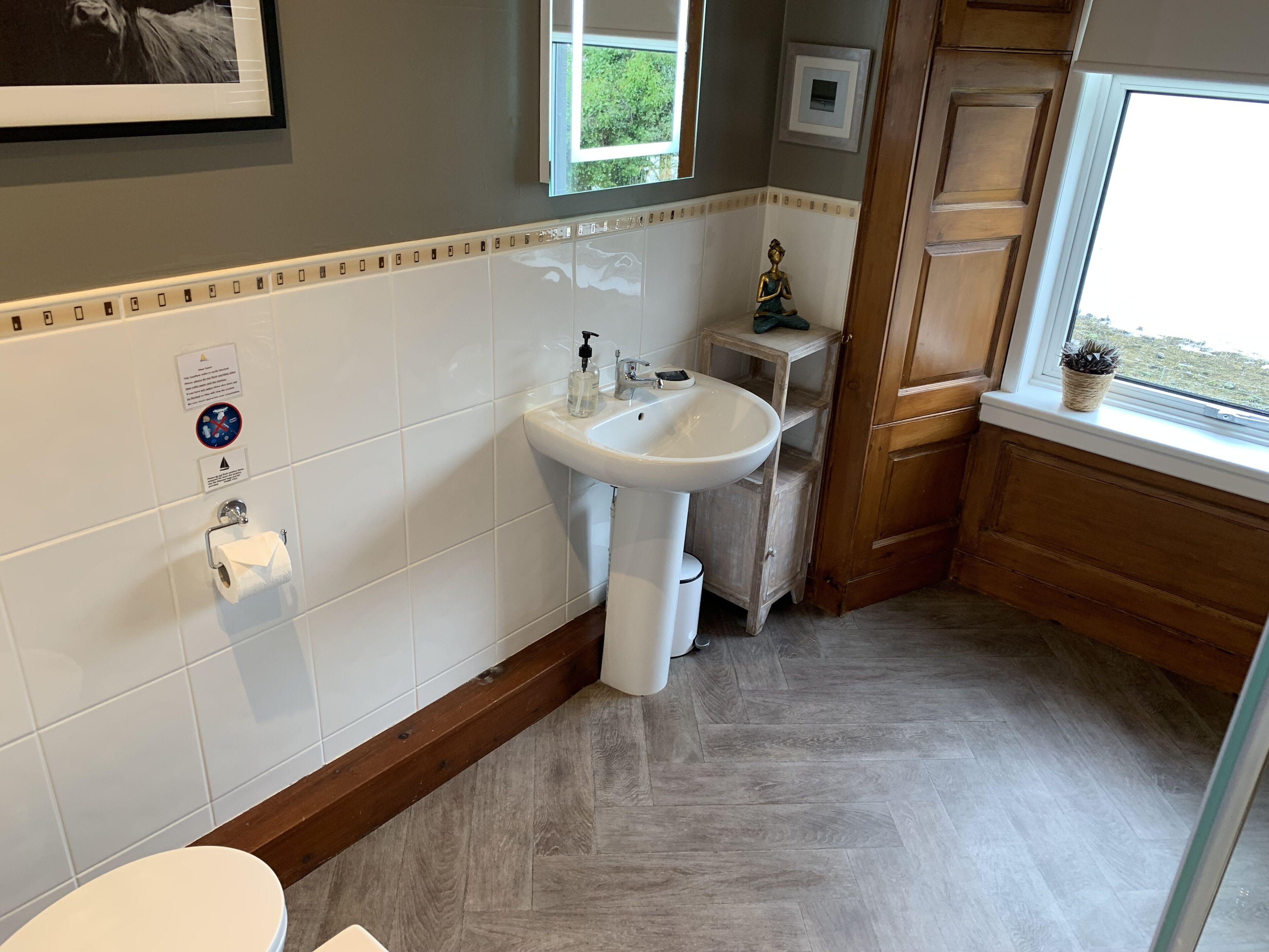 A bathroom with a white sink, toilet, and a wooden vanity.