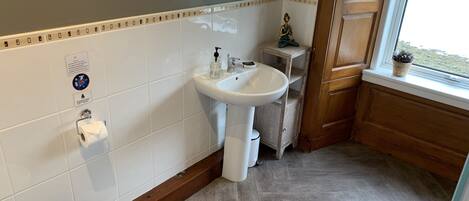 A bathroom with a white sink, toilet, and a wooden vanity.