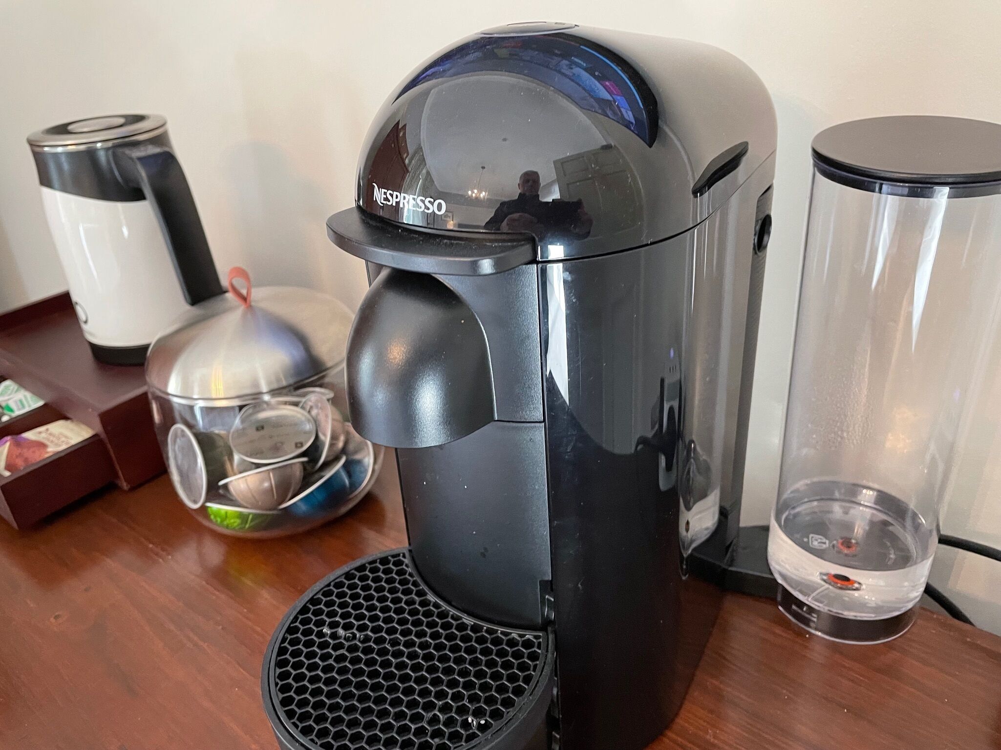 Een koffiezetapparaat met waterreservoir en kan op een houten tafel.