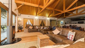 A spacious living area with a high wooden ceiling, large windows, and a view of the outdoors. - The Shore House (Cairndow)