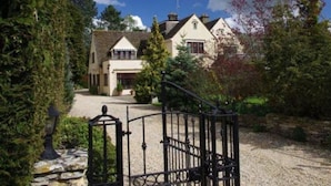 A traditional house with a gravel driveway and a metal gate. - Coombe House (Cheltenham)