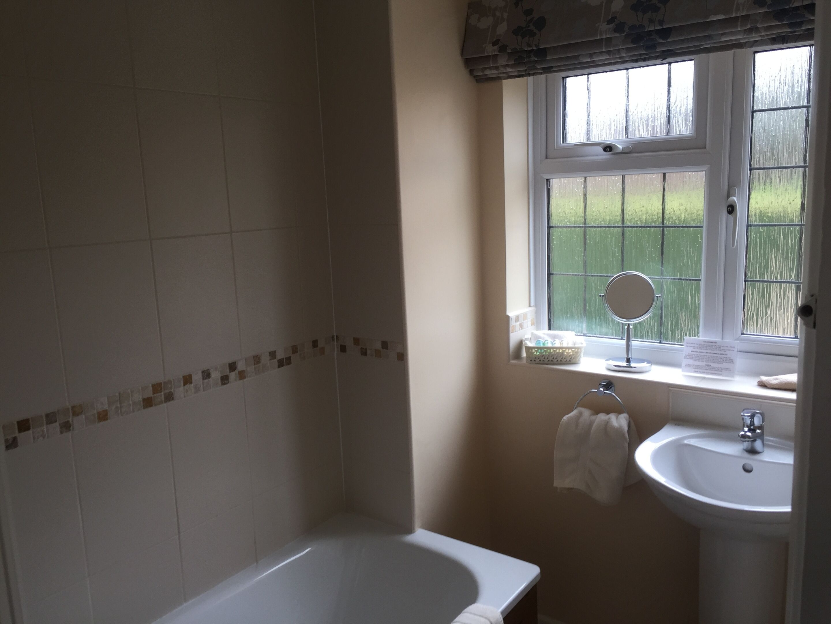A bathroom with a bathtub, a sink, and a window with a view of greenery outside.