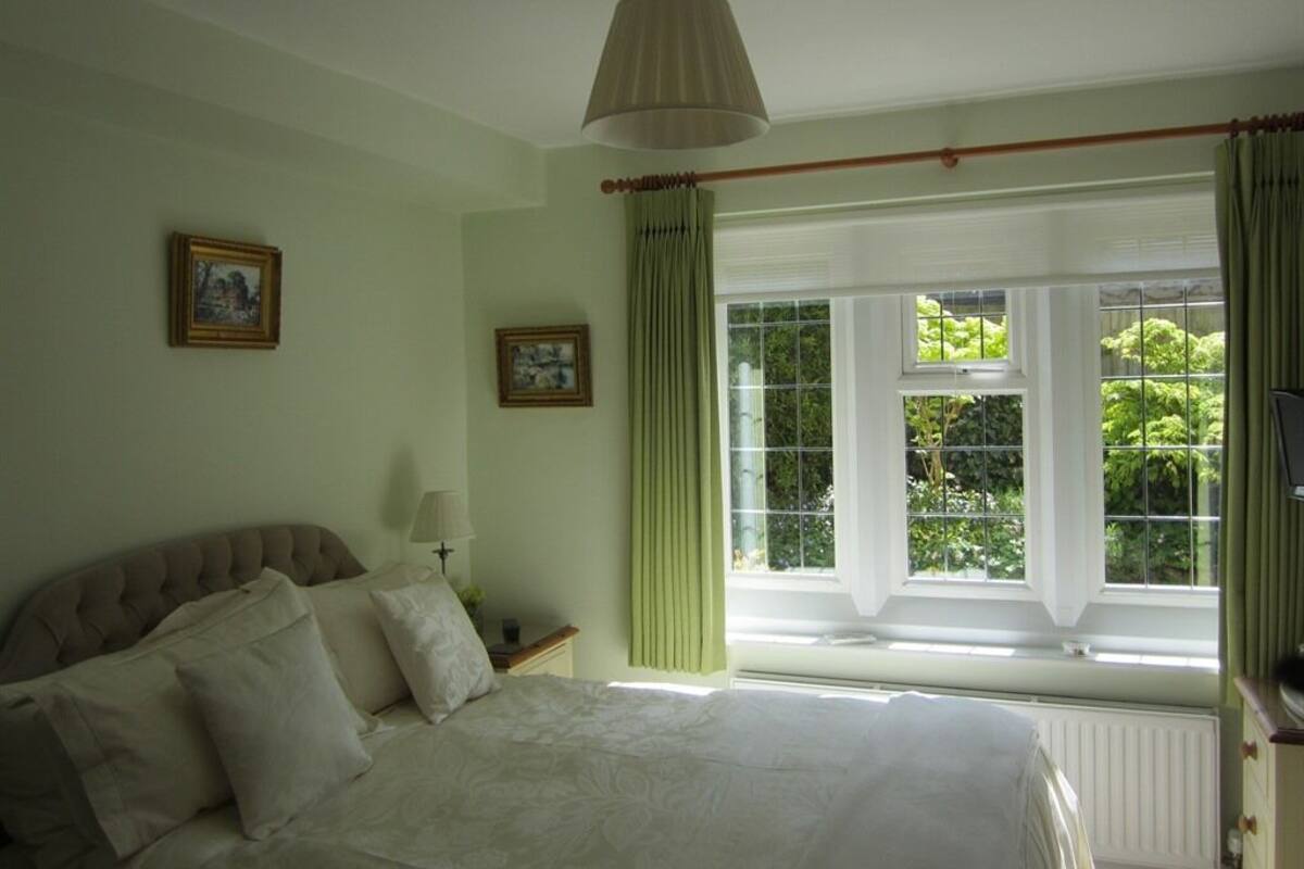 A bedroom with a bed, two bedside tables, a lamp, and a window with curtains.