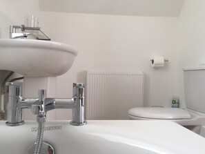 A bathroom with a white sink, chrome faucet, and a toilet. - Coombe House (Cheltenham)