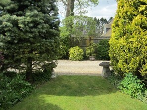 A garden with a gravel path, a stone bench, and various shrubs and trees. - Coombe House (Cheltenham)