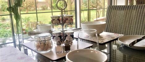A table set for a meal with a view of the garden through a window.