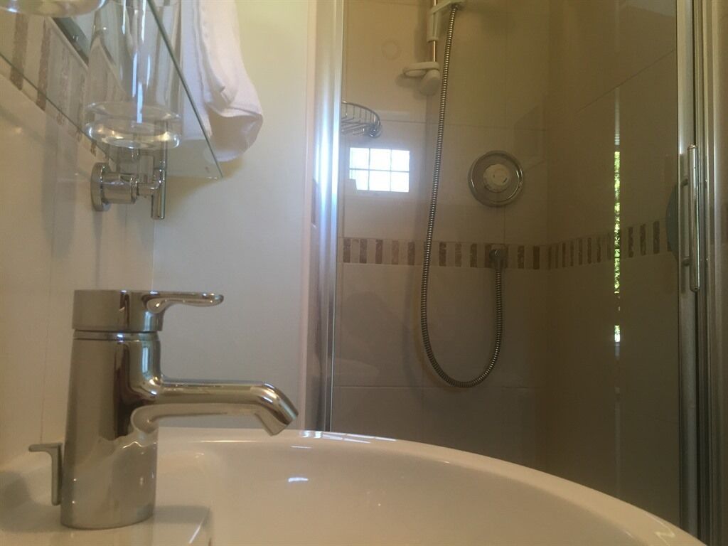 Une salle de bain avec un lavabo, une douche dotée d’une porte en verre et un porte-serviettes.