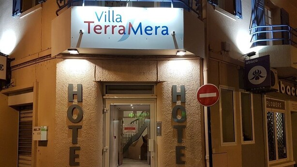 Exterior del Hotel Villa TerraMera con un cartel sobre la entrada, un cartel de 'no entrar' y un letrero de florería.