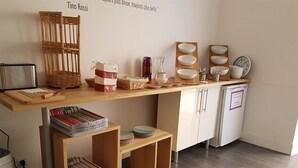 Una cocina con encimera de madera, estantes con platos, un tostador y una cesta.