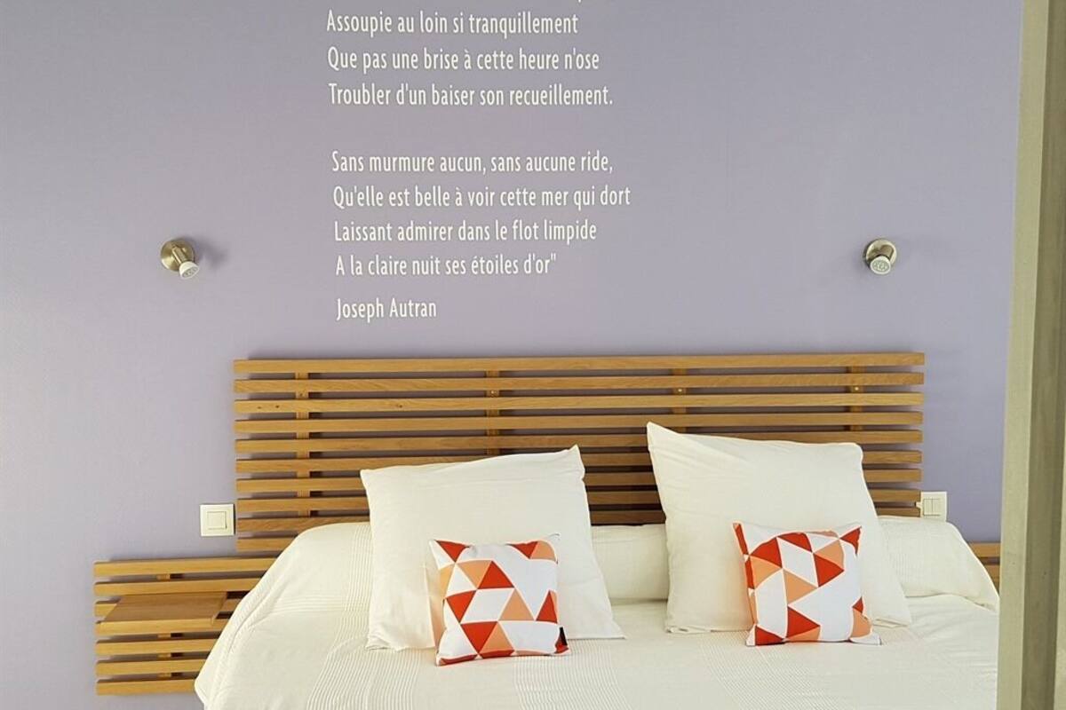 Un dormitorio con cabecera de madera, ropa de cama blanca y almohadas con estampado geométrico.