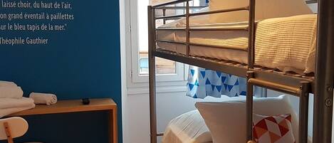 A bunk bed room with a desk, chair, and a window with curtains.