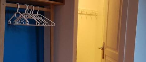 A bathroom with a toilet, a towel rack, and a shelf with folded towels.