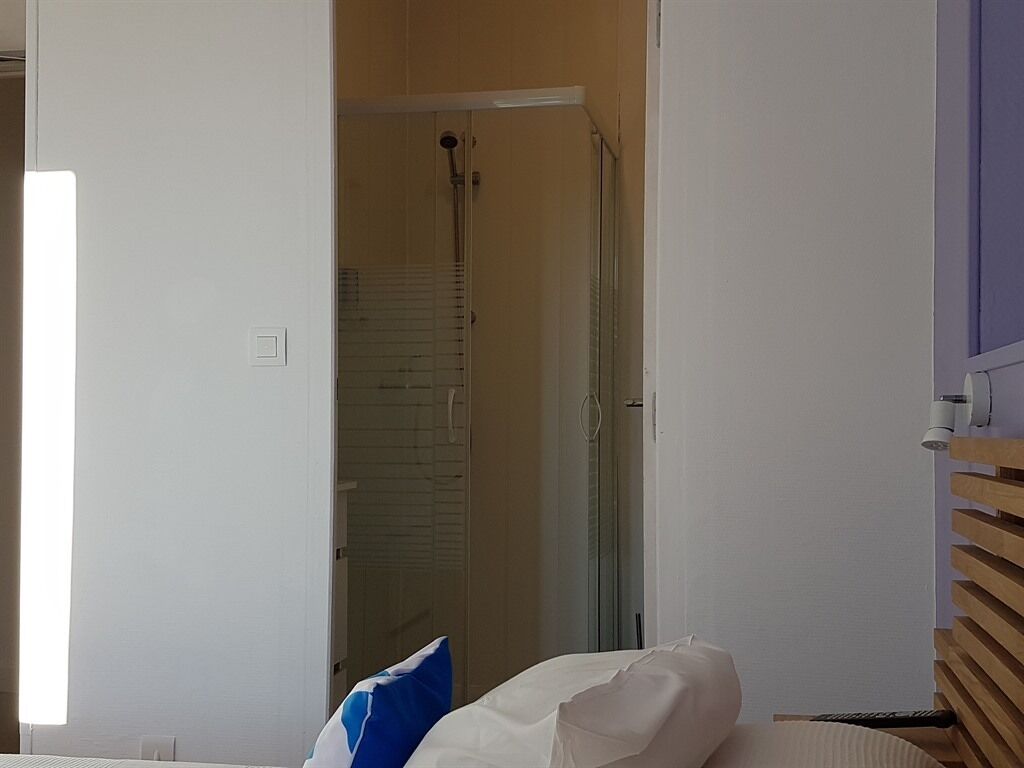 A room with a bed, a shower area, and a wooden panel wall.