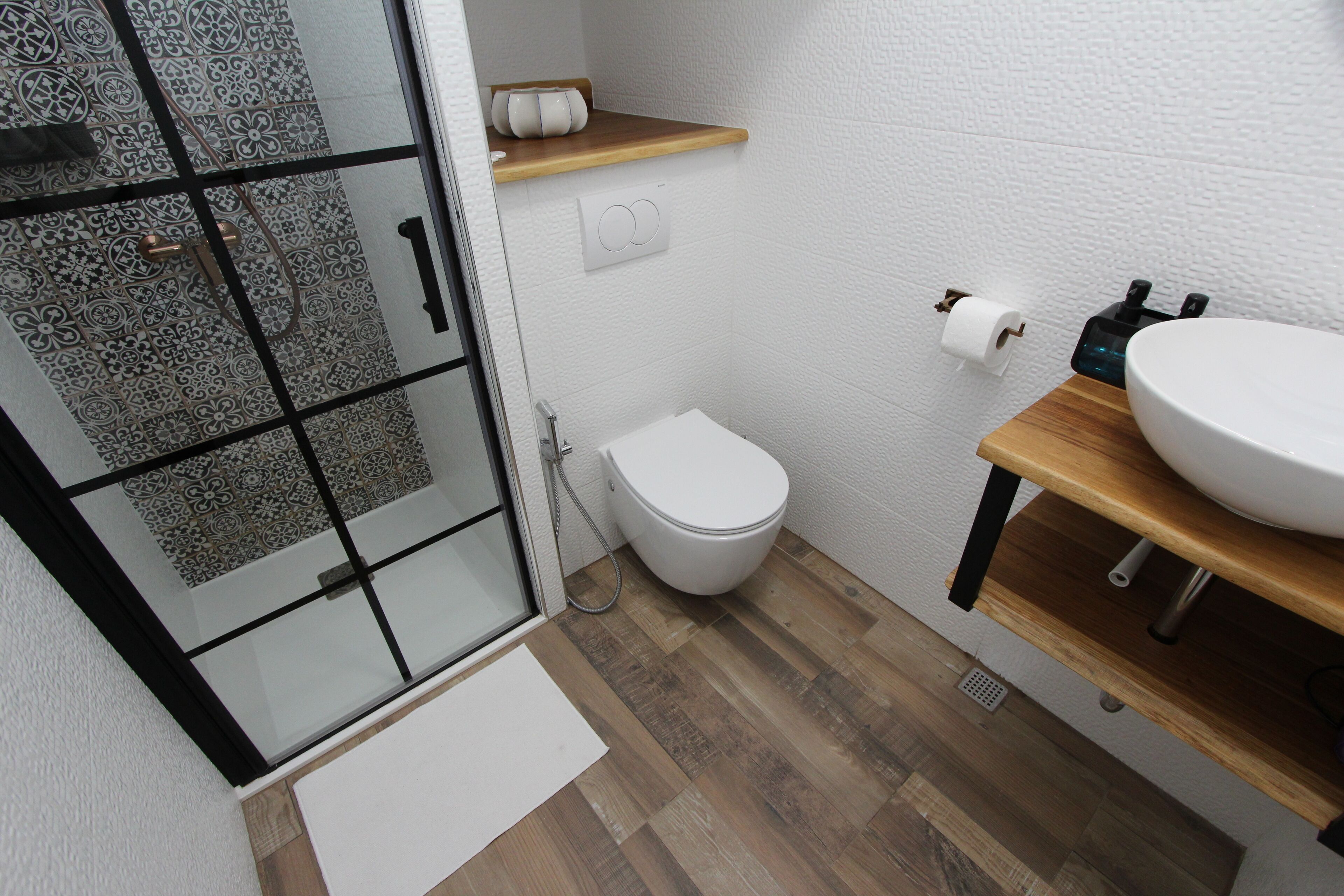 A modern bathroom with a glass shower enclosure, a toilet, and a sink with a wooden countertop.