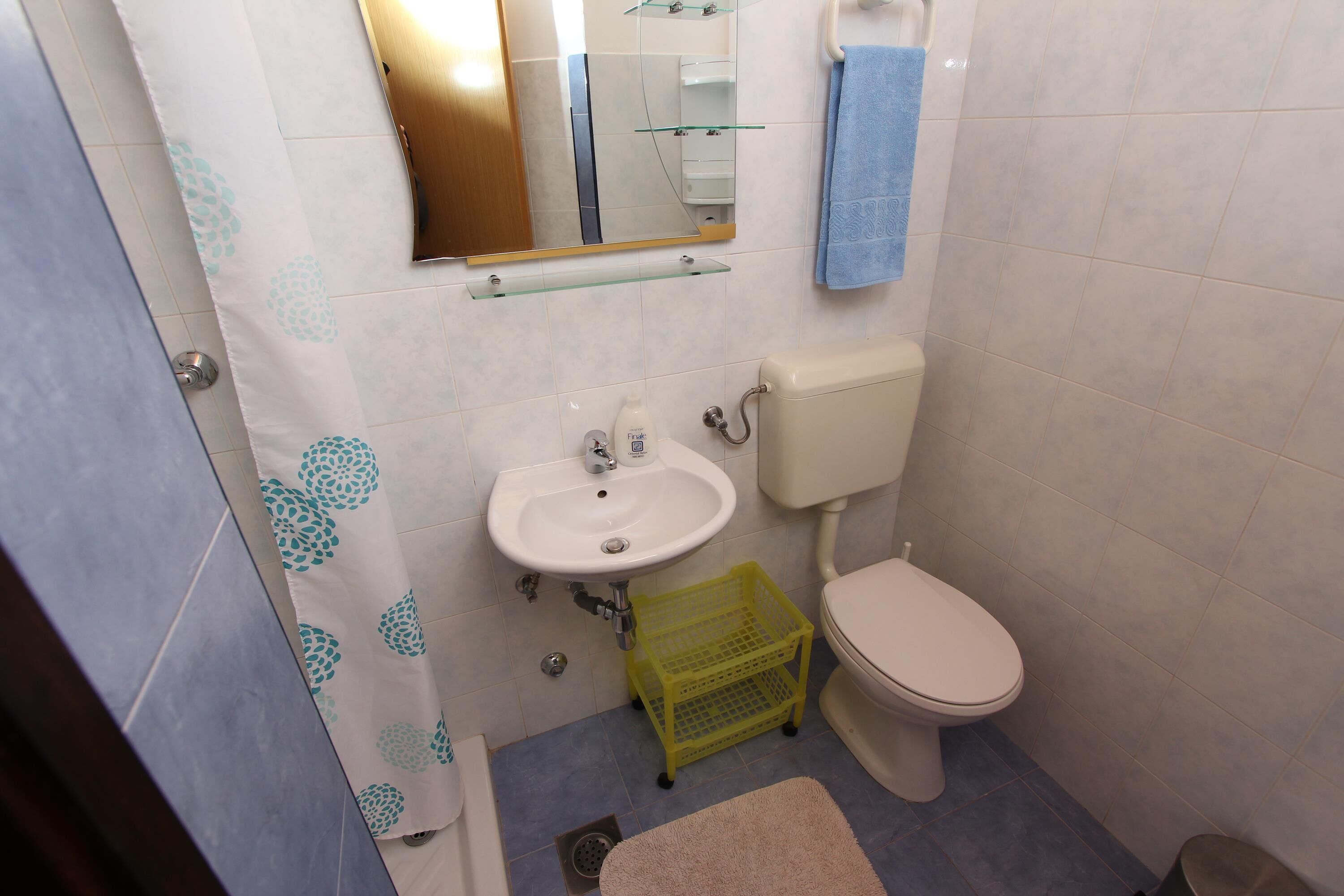 A small bathroom with a sink, toilet, and a mirror.