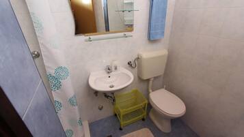 A small bathroom with a sink, toilet, and a mirror.