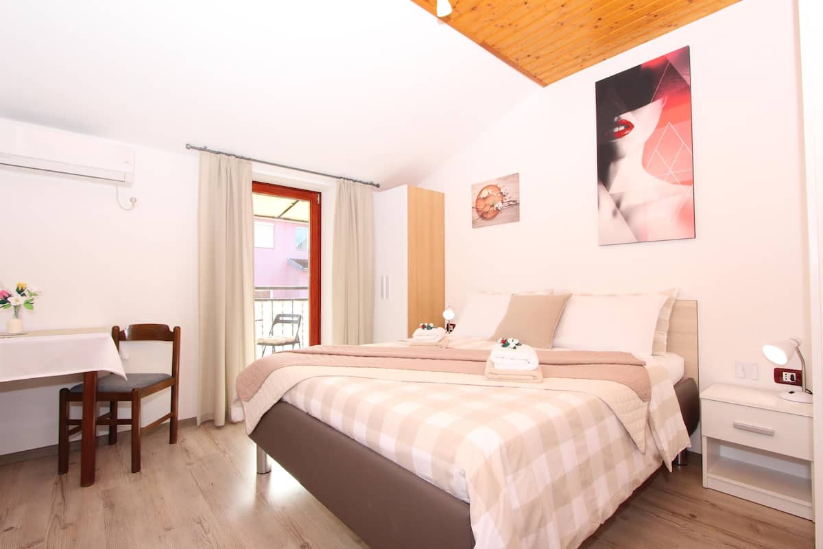 A bedroom with a bed, bedside table, and a desk with a chair.