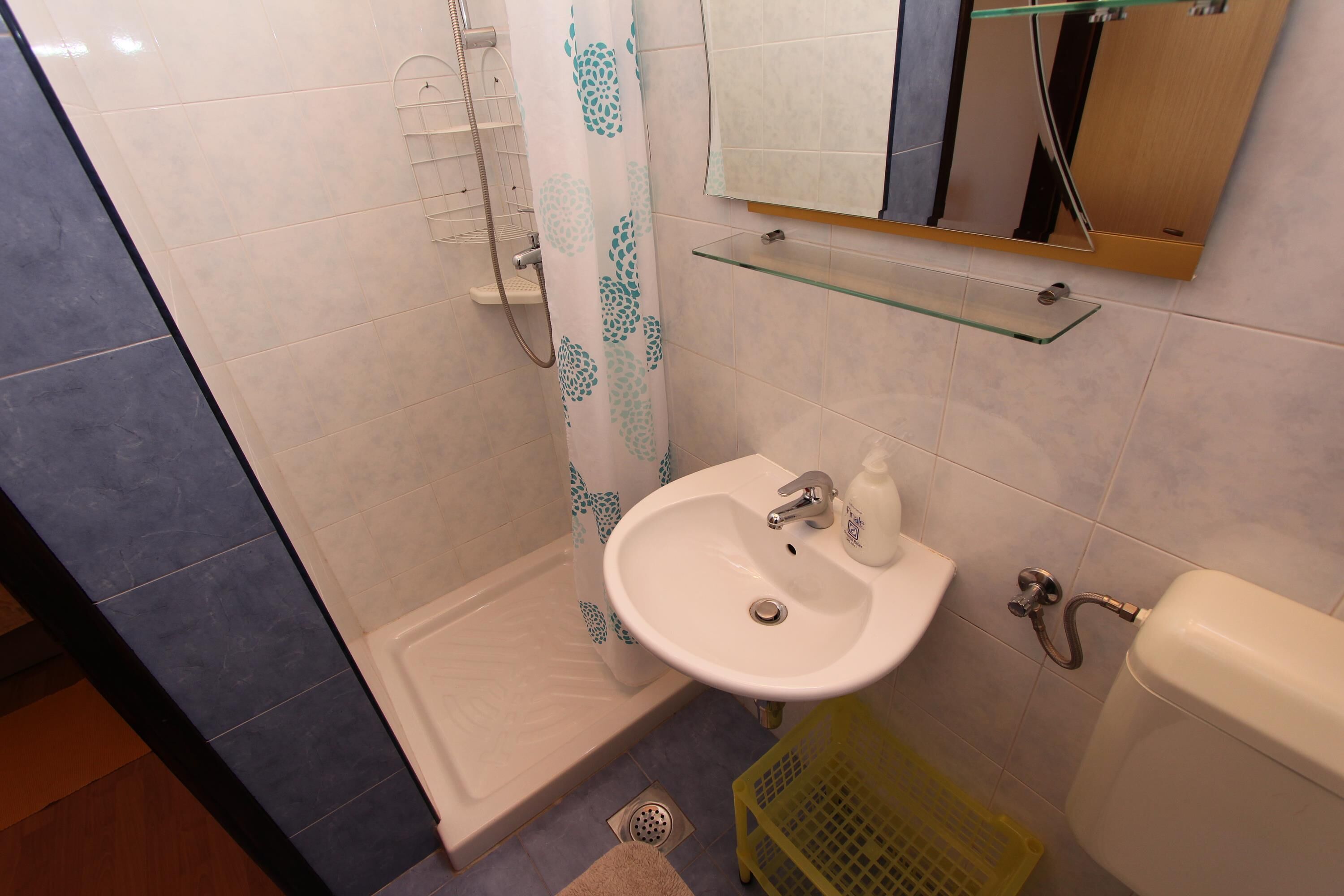 Une salle de bain équipée d’une douche, d’un lavabo, de toilettes et d’une étagère en verre.