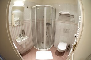 Ein Badezimmer mit einer Duschkabine, einem Waschbecken, einer Toilette und einem Handtuchhalter.