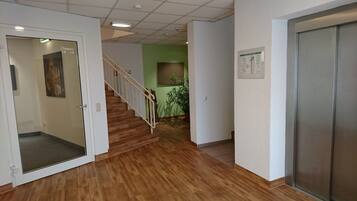 Un pasillo con suelo de madera, una escalera y una pared verde.