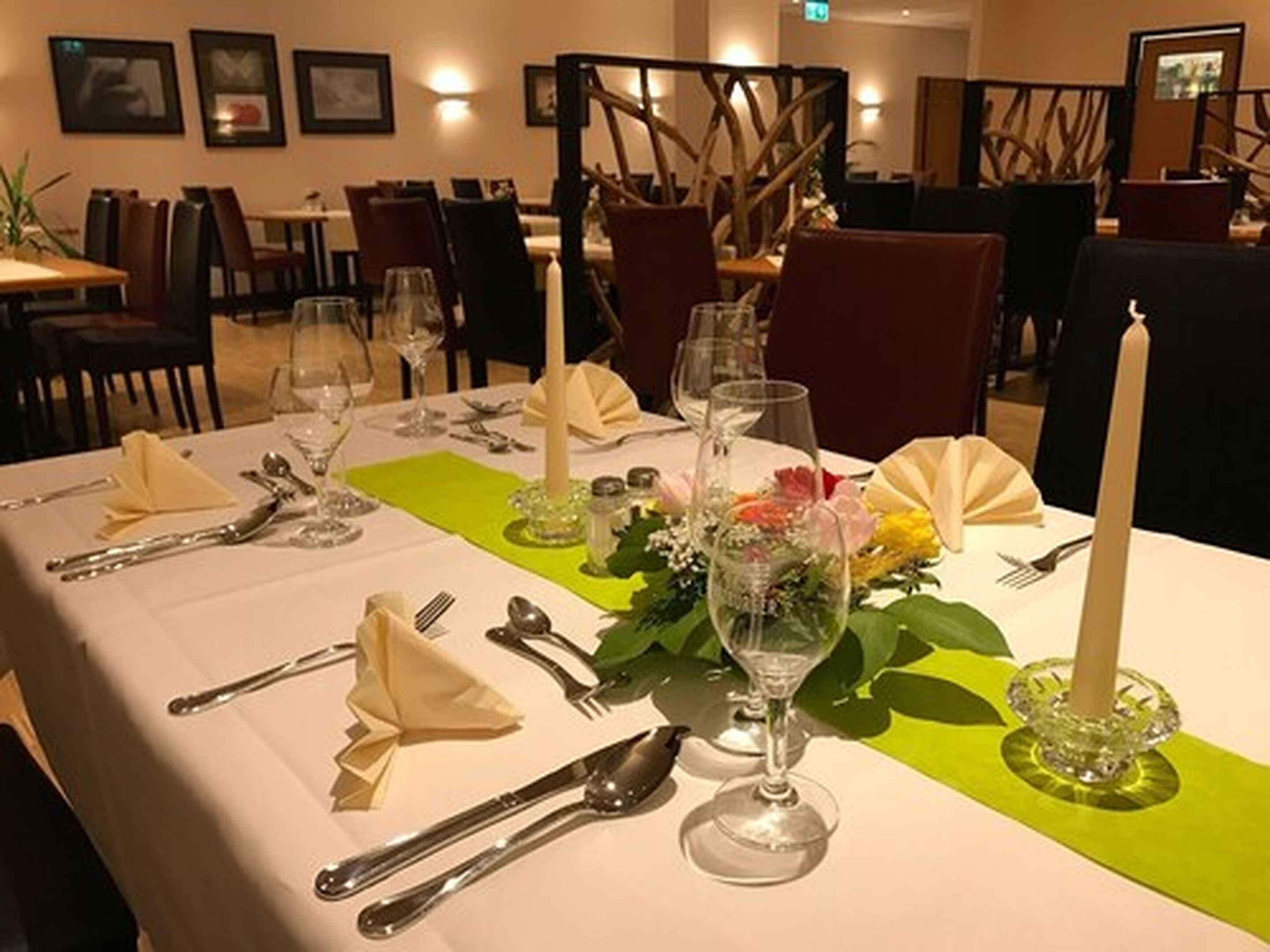 Una mesa de comedor dispuesta con cubiertos, vasos y un centro de mesa.