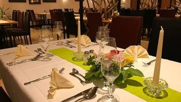 Una mesa de comedor dispuesta con cubiertos, vasos y un centro de mesa.