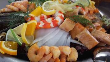 Una bandeja de mariscos con camarones, salmón y rodajas de limón.