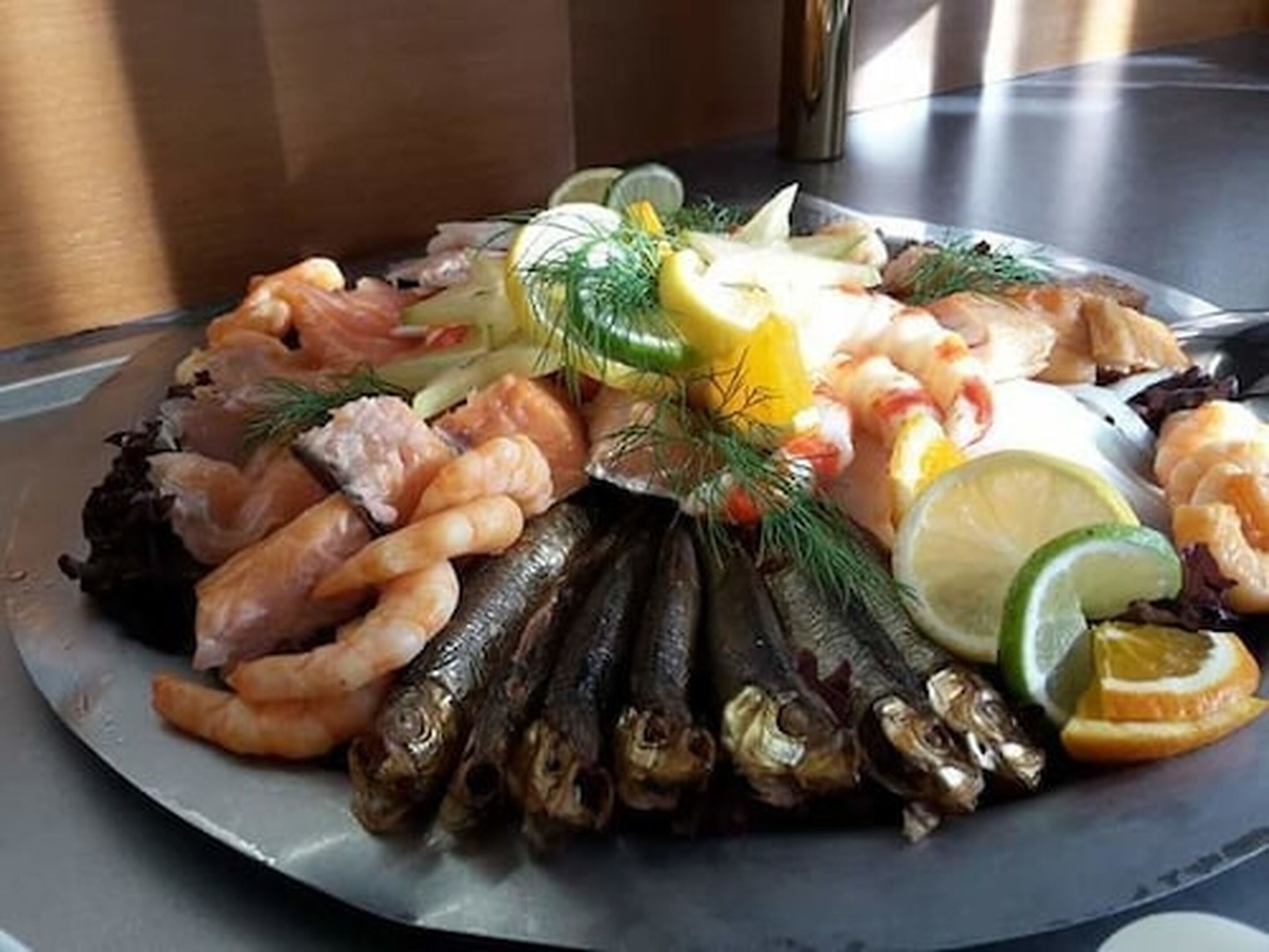 A seafood platter with shrimp, fish, and garnishes on a plate.
