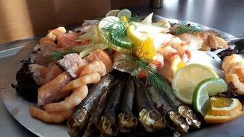 A seafood platter with shrimp, fish, and garnishes on a plate.