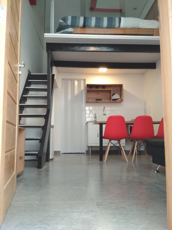 A compact room with a bunk bed, a desk with a chair, and a staircase.