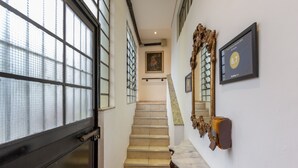 Eine Treppe mit rotem Teppich, die zu einer Zwischenplattform führt. Ein gerahmtes Zertifikat hängt an der Wand darüber.