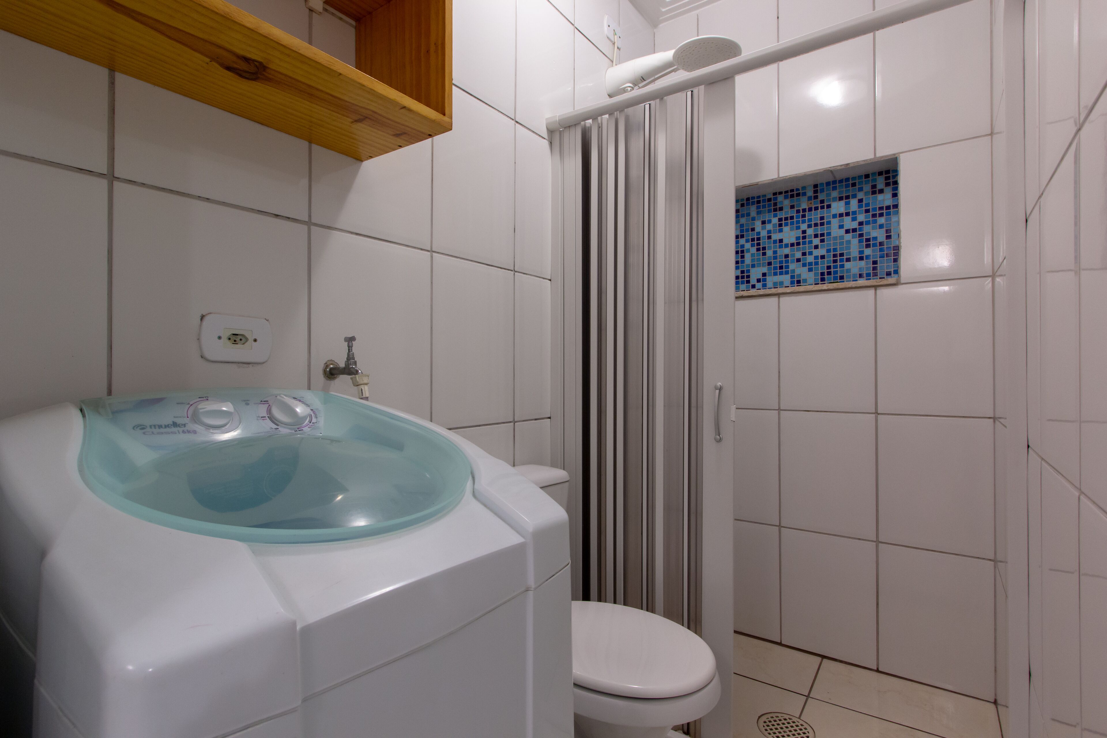 Un baño con lavadora, inodoro y zona de ducha.