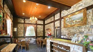 A cozy restaurant with stone walls, wooden ceiling, and a bar area with a large painting. - Pulicity B&B (Puli)