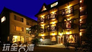 A multi-story hotel with balconies and a well-lit entrance. - Pulicity B&B (Puli)
