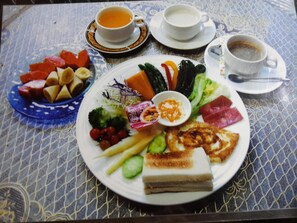 Una mesa con un plato de comida, dos tazas de té y un mantel decorativo.