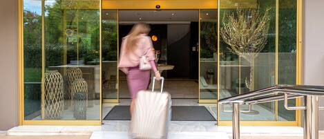 A hotel entrance with a sign reading "Athenean Riviera Hotel & Suites".