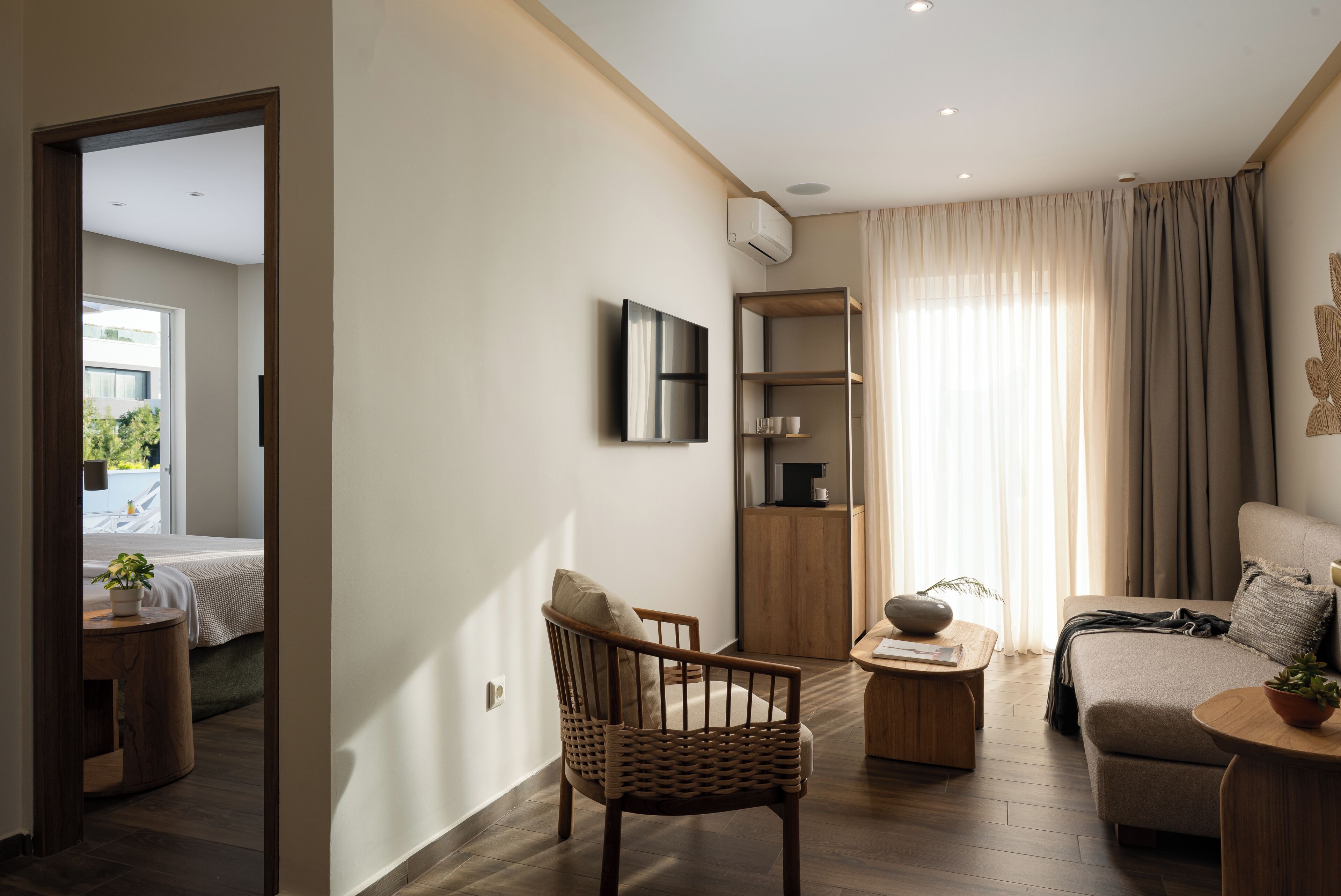 Ein modernes Wohnzimmer mit einer Couch, einem Holzstuhl, einem kleinen Tisch und einem an der Wand befestigten Fernseher.