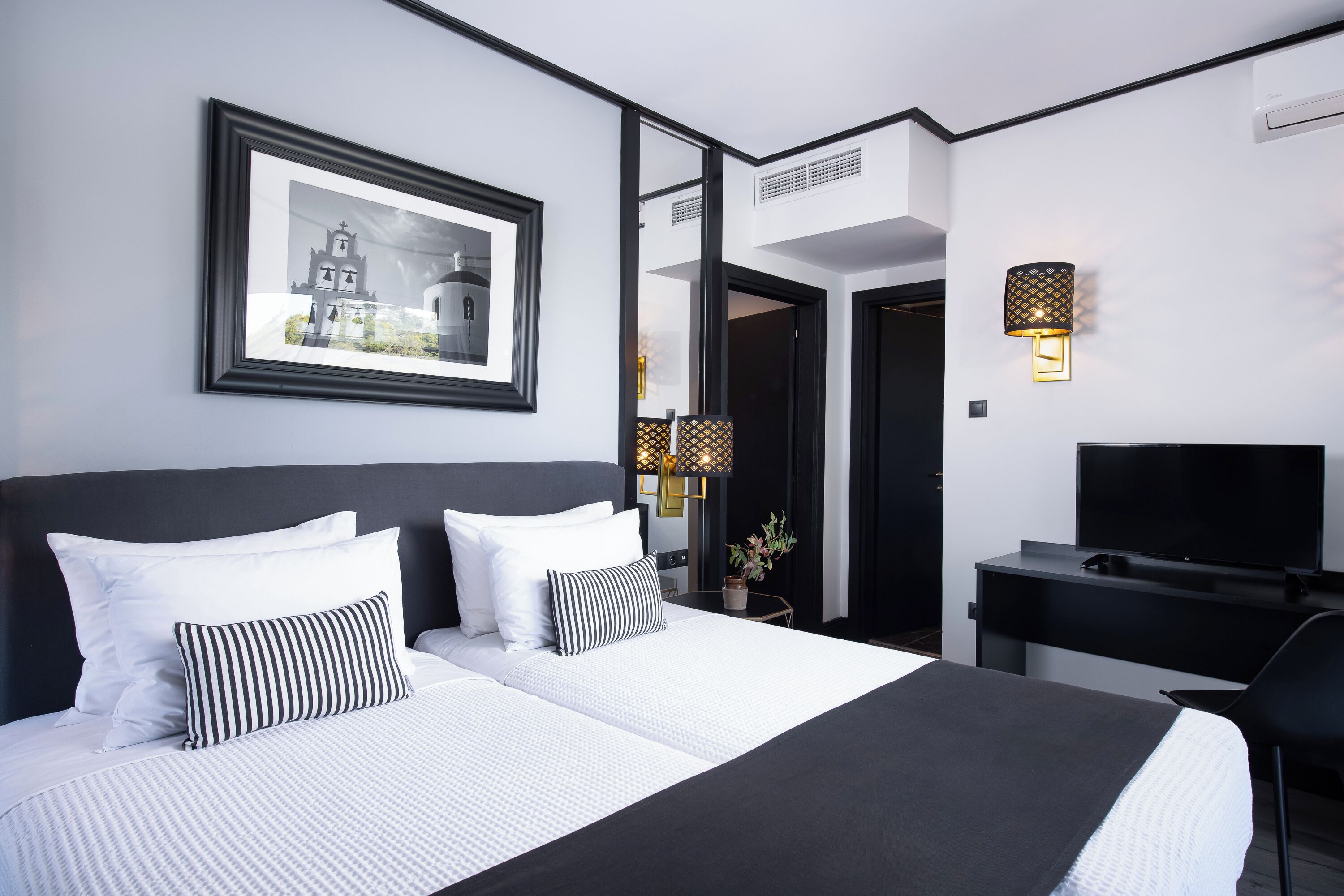 Een moderne hotelkamer met een groot bed, een bureau, een televisie en een ingelijst schilderij aan de muur.