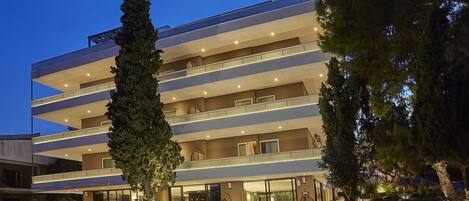 A multi-story hotel with a modern design, featuring balconies and a well-lit entrance.